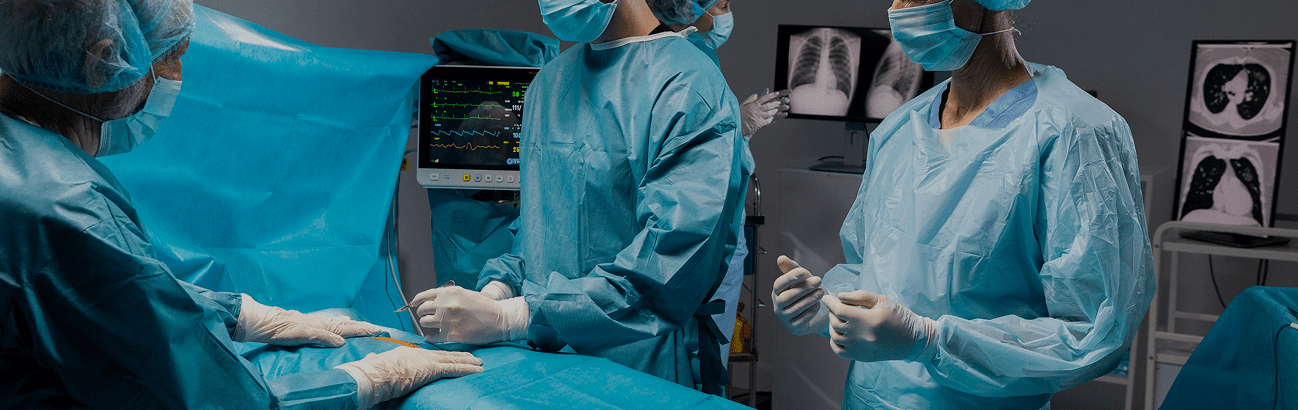 Surgical team in sterile gowns performing a procedure in a hospital operating theater with patient monitoring equipment